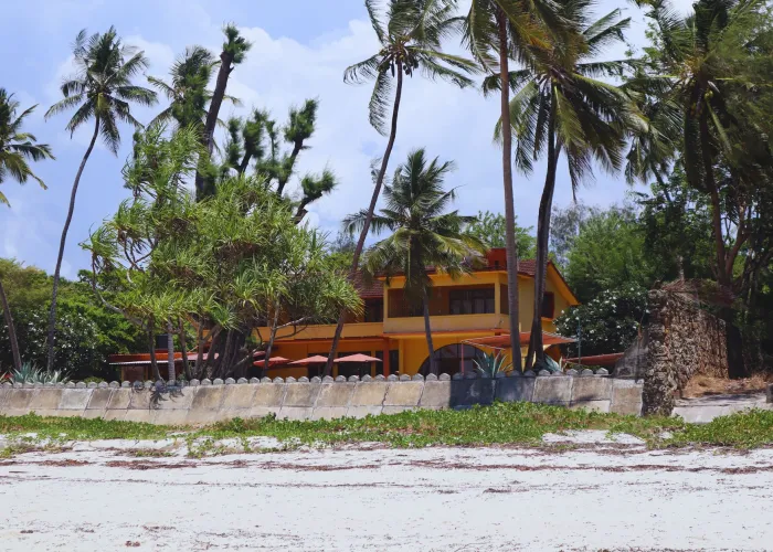 A serene beachfront house in Mombasa, Kenya, surrounded by palm trees and lush greenery.