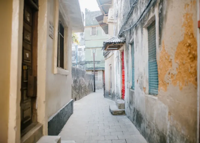 Paved narrow street between aged stone residential houses with shabby facade in city