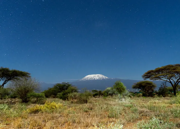 A breathtaking view of Mount Kilimanjaro framed by a clear starry night sky from Kajiado County, Kenya.