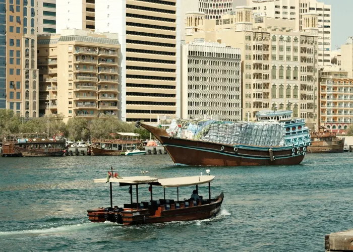 Traditional wooden boats at Dubai Creek with city skyline in the background.